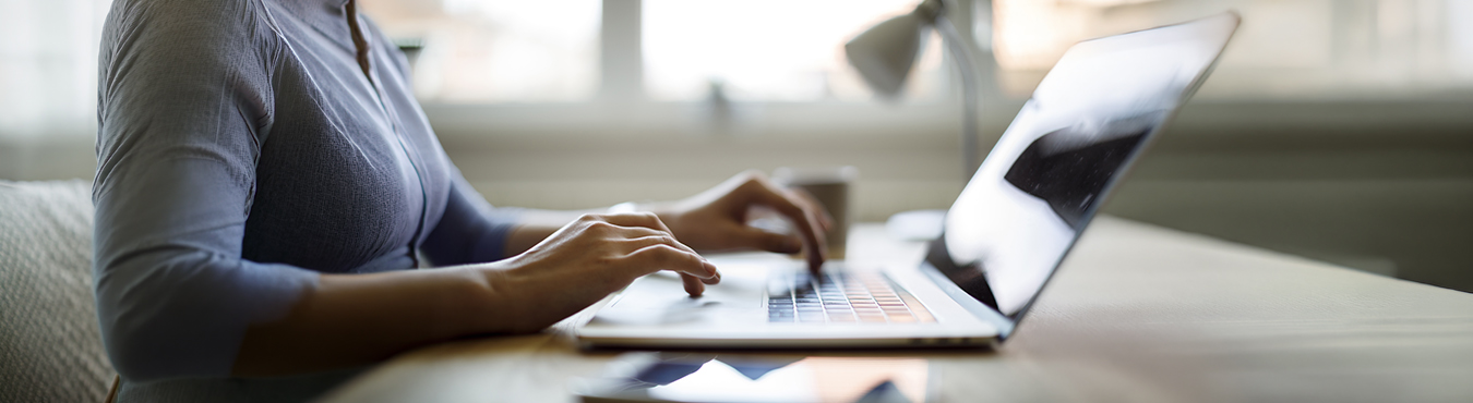 Eine Person tippt auf Tastatur eines Laptops